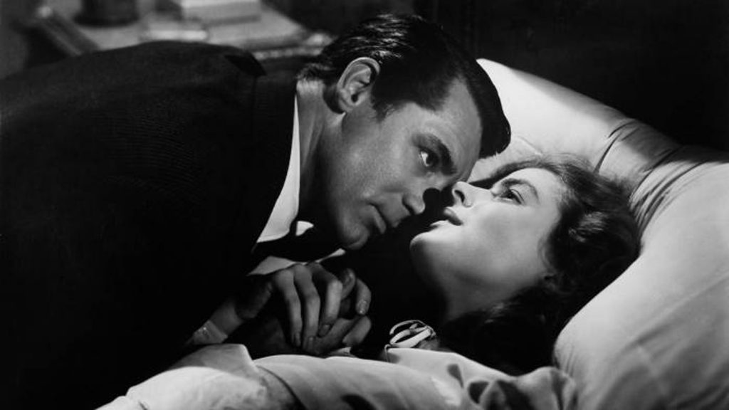Cary Grant menacingly leans over Ingrid Bergman in bed.