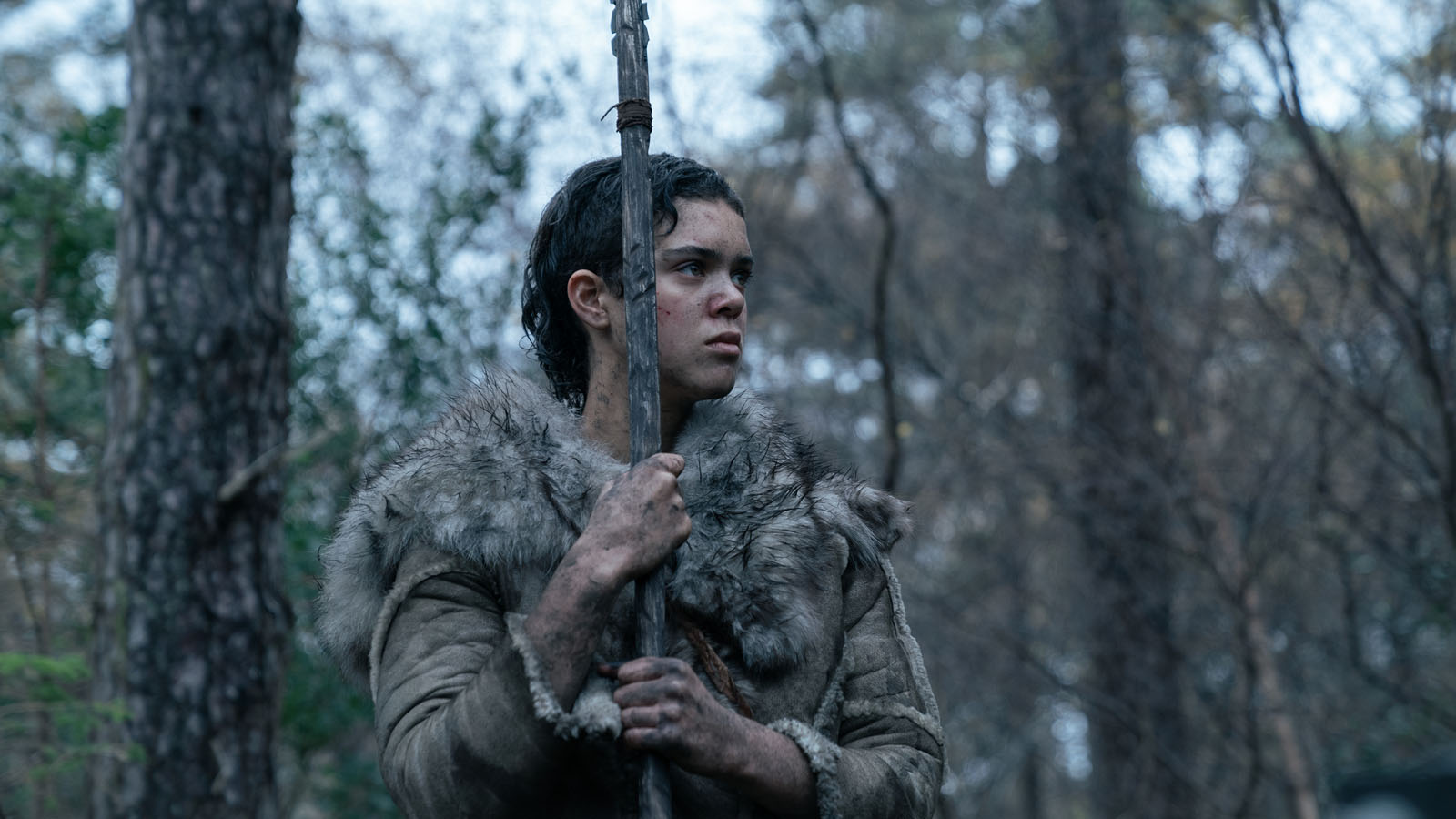 A girl in furs hold a manmade spear.